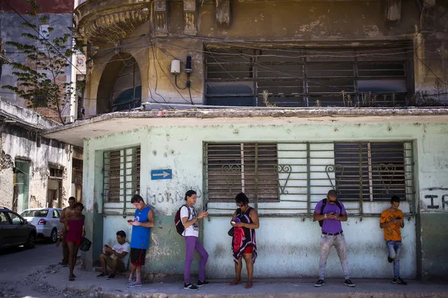 Pedestrians use their smartphones to surf the internet in Havana, Cuba, Wednesday, August 22, 2018. (Photo by Desmond Boylan/AP Photo)