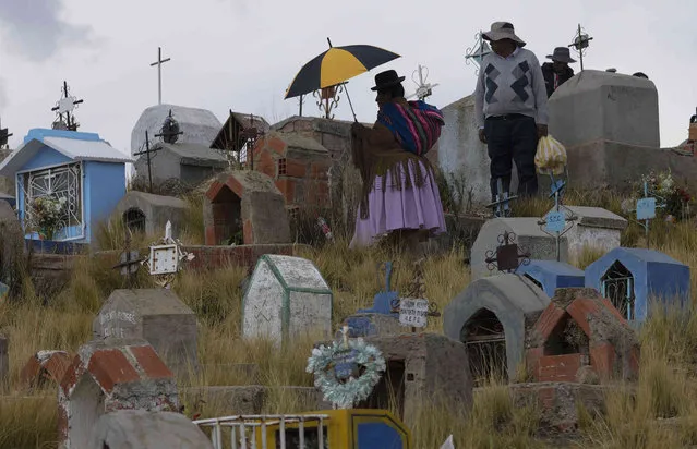 People visit the grave of a relative on the Day of the Dead at the Villa Ingenio cemetery in El Alto, Bolivia, Thursday, November 2, 2023. The Day of the Dead honors the deceased, a tradition that coincides with All Saints Day and All Souls Day celebrated on Nov. 1 and 2. (Photo by Juan Karita/AP Photo)