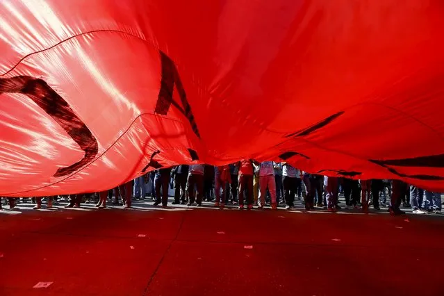 Protesters march as they hold a flag during a demonstration against the government to demand changes in the education system at Santiago, April 16, 2015. (Photo by Ivan Alvarado/Reuters)