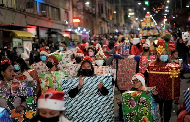 People dressed as Christmas gifts dance during the annual Christmas Parade in La Paz, Bolivia, Friday, November 25, 2022. The parade is organized by the merchants of the annual Christmas Fair, who dress as stars, elves, angels, snowflakes, reindeers and other traditional figures associated with the holidays. (Photo by Juan Karita/AP Photo)