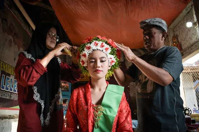 A woman in a traditional dress is helped by her parents to prepare a flower decoration for her hair to participate in the Ngarot Festival, which marks the start of the rice planting season in Lelea, West Java, on December 13, 2023. (Photo by Timur Matahari/AFP Photo)