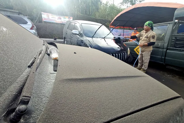 A disaster management agency official washes a car covered in volcanic ash from the eruption of Mount Marapi in Agam, West Sumatra, Indonesia, Sunday, January 14, 2024. Dozens of people living on the slopes of Mount Marapi have been evacuated from their homes after Indonesian authorities raised the alert level of of the nearly 2,900-meter (9,480-foot) volcano to the second highest as it continues to erupt. (Photo by Givo Alputra/AP Photo)