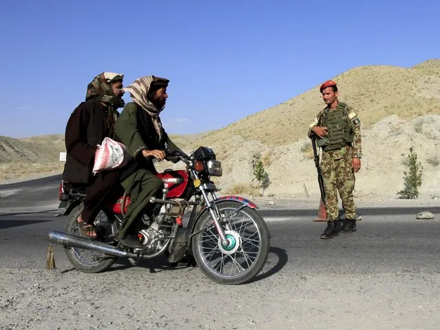 An Afghan National Army (ANA) soldier watches two men pass by on a motorcycle at a checkpoint on the outskirts of Jalalabad province, Afghanistan, in this June 29, 2015 file photo. NATO advisers want Afghan soldiers to spend less time manning checkpoints and more taking the fight to Taliban militants, a key tactical shift the coalition hopes will enable local forces to quell a rising insurgency. (Photo by Reuters/Pariwz)