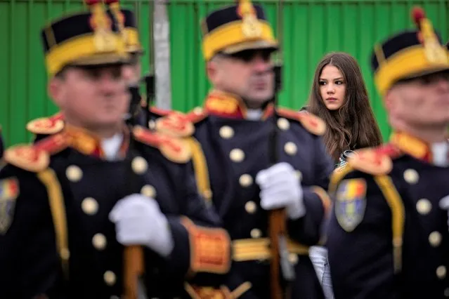 A girl stands behind an honor guard outside the Heroes' Cemetery in Bucharest, Romania, Wednesday, December 21, 2022, after a memorial religious service for those killed in the 1989 anti-communist uprising. Participants and relatives of those killed marked the 33rd anniversary of the anti-communist uprising which started in Bucharest on Dec. 21, 1989 and left more than one thousand people dead and ended the rule of dictator Nicolae Ceausescu. (Photo by Vadim Ghirda/AP Photo)
