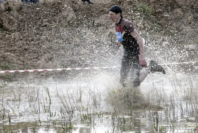 Participant runs though a water pool as he competes during the Strong Race event near Tukums, Latvia May 3, 2015. (Photo by Ints Kalnins/Reuters)