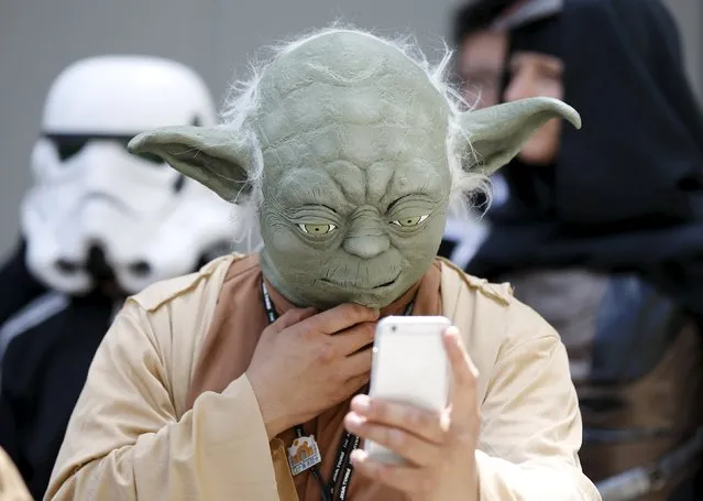 A cosplayer dressed as Star Wars character Yoda looks at a mobile phone at a Star Wars Day fan event in Tokyo May 4, 2015. (Photo by Toru Hanai/Reuters)