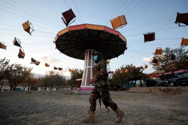 A Taliban fighter walks past a ride as he takes a day off to visit the amusement park at Kabul's Qargha reservoir in the outskirts of Kabul, Afghanistan on October 29, 2021. (Photo by Zohra Bensemra/Reuters)