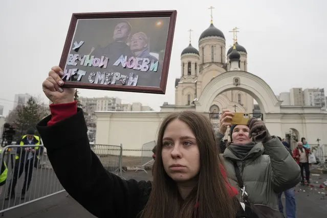 A woman holds a portrait of Alexei Navalny, left, and his wife Yulia, signed “Eternal love has no death” outside the Church of the Icon of the Mother of God Soothe My Sorrows, in Moscow, Russia, Friday, March 1, 2024. Relatives and supporters of Alexei Navalny are bidding farewell to the opposition leader at a funeral in southeastern Moscow, following a battle with authorities over the release of his body after his still-unexplained death in an Arctic penal colony. (Photo by AP Photo)