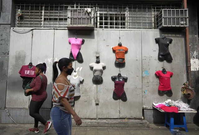 Residents walk past mannequins displaying women's clothes for sale in Caracas, Venezuela, Friday, October 1, 2021. (Photo by Ariana Cubillos/AP Photo)