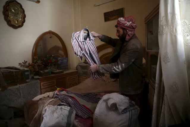 A man inspects a shirt of his dead son, who died the day before, after an airstrike in the rebel-held besieged city of Douma, a suburb of Damascus, Syria February 27, 2016. (Photo by Bassam Khabieh/Reuters)