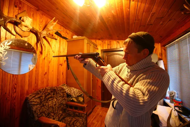 Vladimir Krivenchik, a hunter, checks weapon in his house in the village of Khrapkovo, Belarus February 3, 2017. (Photo by Vasily Fedosenko/Reuters)