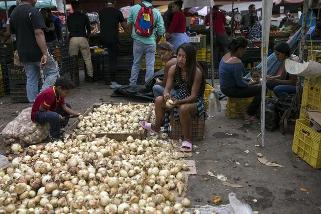 Vendors clean onions at the Coche Market in Caracas, Venezuela, Thursday, May 2, 2019. Farmers truck in the produce, meat and coffee from miles around the capital to the market known for its low prices. Its customers include everybody from restaurant owners to homemakers. (Photo by Rodrigo Abd/AP Photo)