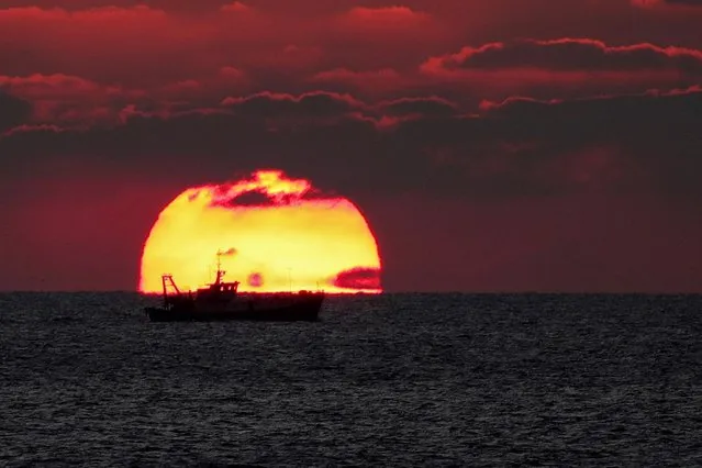 A fishing boat is pictured as it passes by during sunset in Durres, Albania, October 19, 2021. (Photo by Florion Goga/Reuters)