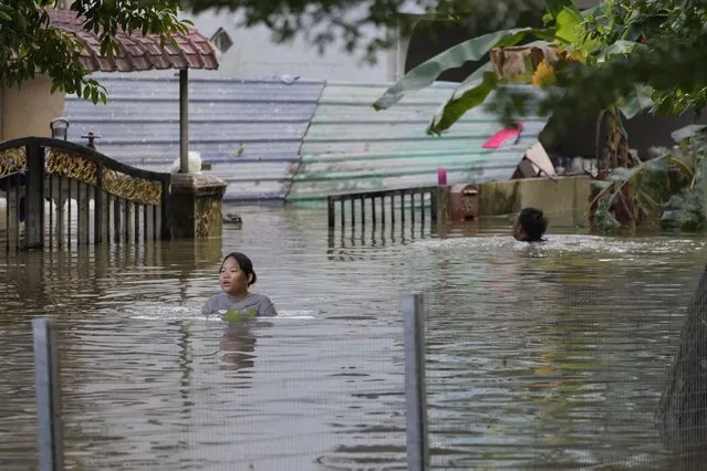 Residents wade through a flooded road as they were trapped at their house due to flooding in Shah Alam, on the outskirts of Kuala Lumpur, Malaysia, Monday, December 20, 2021. Rescue services on Monday worked to free thousands of people trapped by Malaysia's worst flooding in years after heavy rains stopped following more than three days of torrential downpours in the capital and around the country. (Photo by Vincent Thian/AP Photo)