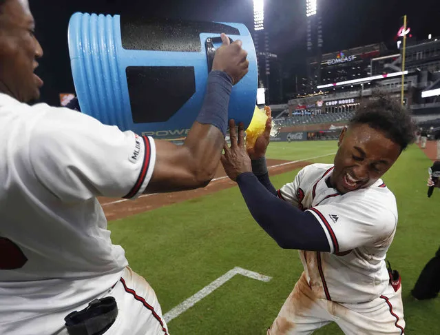 Atlanta Braves' Ozzie Albies, right, is doused by Ronald Acuna Jr., after driving in the winning run with a double in the 11th inning of a baseball game against the Pittsburgh Pirates early Thursday, June 13, 2019, in Atlanta. The Braves won 8-7. (Photo by John Bazemore/AP Photo)