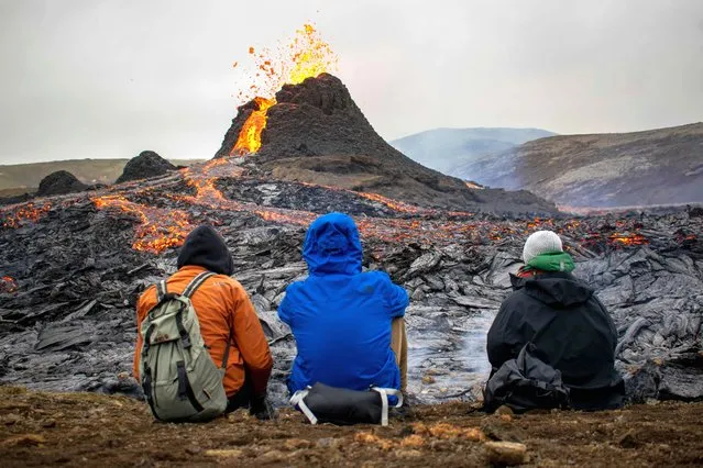 Sunday hikers look at the lava flowing from the erupting Fagradalsfjall volcano some 40 km west of the Icelandic capital Reykjavik, on March 21, 2021. Weekend hikers took the opportunity Sunday to inspect the area where a volcano erupted in Iceland on March 19, some 40 kilometres (25 miles) from the capital Reykjavik, the Icelandic Meteorological Office said, as a red cloud lit up the night sky and a no-fly zone was established in the area. (Photo by Jeremie Richard/AFP Photo)