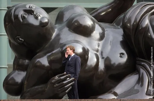 A city worker talks on his mobile phone next to a giant sculpture of a woman entitled Broadgate Venus