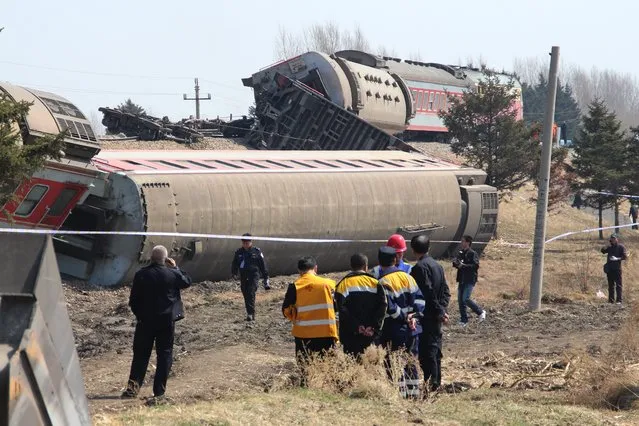 Rescuers and investigators are seen at the site where a train derailed in the Hailun country of Suihua City, northeast China's Heilongjiang province, 13 April 2014. A passenger train which runs from Heihe to Harbin, derailed at the section in Hailun county in the early morning hours of 13 April 2014, causing 15 passengers suffering injuries, according to local media reports. A cause for the accident was not immediately reported.  (Photo by EPA/STR)
