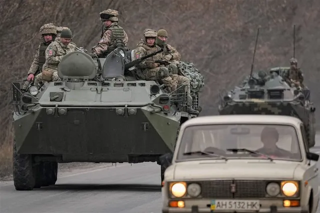 Ukrainian servicemen sit atop armored personnel carriers driving on a road in the Donetsk region, eastern Ukraine, Thursday, February 24, 2022. (Photo by Vadim Ghirda/AP Photo)