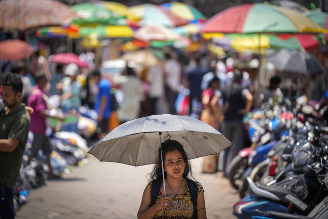 A woman walks under an umbrella as heat wave grips the city of Guwahati, India, Saturday, May 25, 2024. Most parts of the north India are sweltering under scorching temperatures with the capital New Delhi under a severe weather alert as extreme temperatures strike parts of the country. (Photo by Anupam Nath/AP Photo)