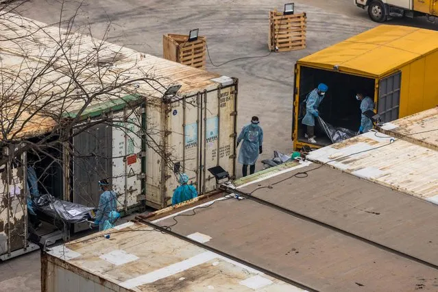 Workers move the bodies of deceased people from a truck into a refrigerated container at the Fu Shan Public Mortuary in Hong Kong on March 16, 2022, amid the city's worst-ever Covid-19 coronavirus outbreak that has seen overflowing hospitals and morgues and a frantic expansion of the city's spartan quarantine camp system. (Photo by Dale de la Rey/AFP Photo)