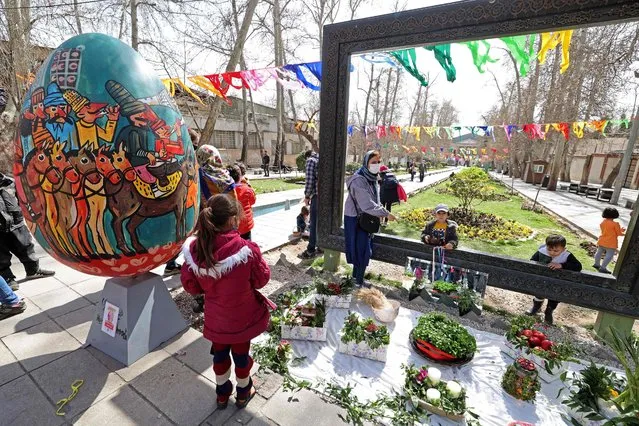 Iranians take photo with a traditional Haftsin, a symbolic arrangement of seven items whose names start with the letter “S”, at a park during an event organised by the municipality of Tehran on March 16, 2022, ahead of the celebration of Noruz, the Persian New Year. Noruz (Nowruz), begins on March 20 and coincides with the first day of spring during which locals revive the ancient Zoroastrian celebration of lighting a fire and dancing around the flame. (Photo by Atta Kenare/AFP Photo)