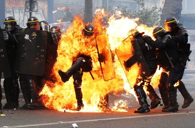 French CRS anti- riot police officers are engulfed in flames as they face protesters during a march for the annual May Day workers' rally in Paris on May 1, 2017. (Photo by Zakaria Abdelkafi/AFP Photo)