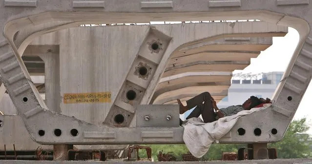 An Indian laborer sleeps under a concrete sections of a fly over bridge on a hot summer afternoon in Hyderabad, India, Friday, May 20, 2016. The prolonged heat wave this year has already killed hundreds and destroyed crops in more than 13 states. (Photo by Mahesh Kumar A./AP Photo)