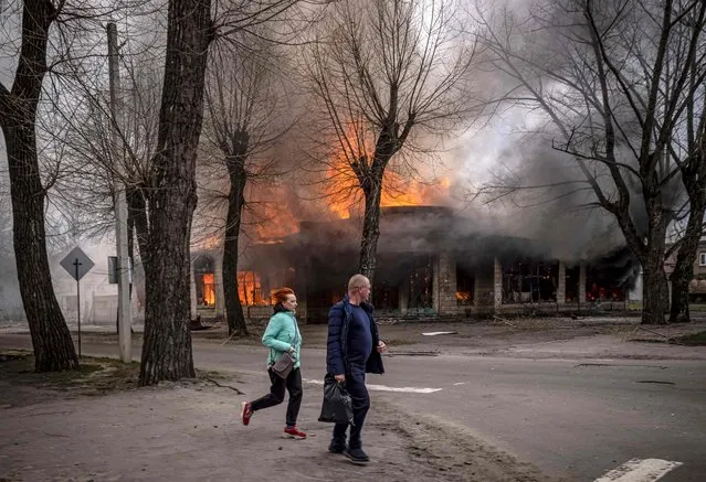 Residents run near a burning house following a shelling Severodonetsk, Donbass region, on April 6, 2022, as Ukraine tells residents in the country's east to evacuate “now” or “risk death” ahead of a feared Russian onslaught on the Donbas region, which Moscow has declared its top prize. NATO believes Moscow aims to take control of the whole Donbas region in eastern Ukraine with the aim of creating a corridor from Russia to annexed Crimea. (Photo by Fadel Senna/AFP Photo)