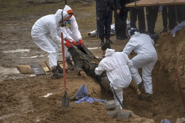 Cemetery workers remove a body from a mass grave, for identification in a morgue, in Bucha, on the outskirts of Kyiv, Ukraine, Sunday, April 10, 2022. (Photo by Rodrigo Abd/AP Photo)