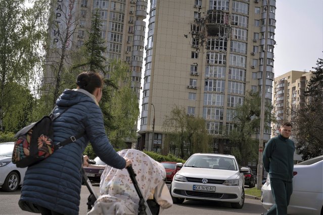 People pass by an apartment building damaged by a drone that was shot down, during a Russian overnight strike, amid Russia's attack, in Kyiv, Ukraine, Monday, May 8, 2023. (Photo by Andrew Kravchenko/AP Photo)