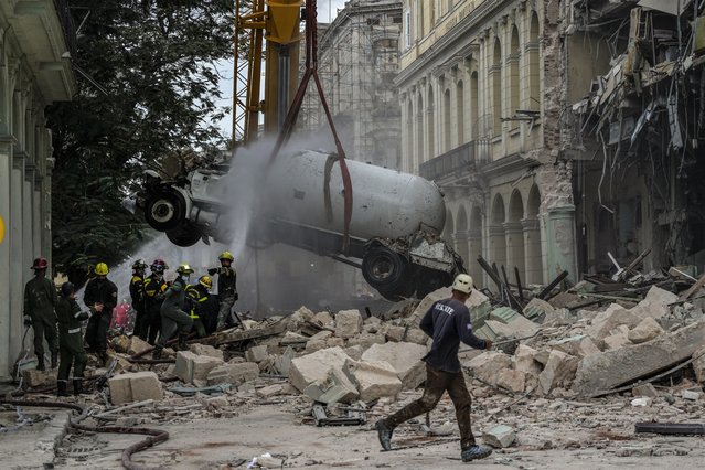 Firefighters spray a tanker truck with water in order to cool it down as they remove it from the site of a deadly explosion that destroyed the five-star Hotel Saratoga, in Havana, Cuba, Friday, May 6, 2022. A powerful explosion apparently caused by a natural gas leak killed at least 18 people, including a pregnant woman and a child, and injured dozens Friday when it blew away outer walls from the luxury hotel in the heart of Cuba’s capital. (Photo by Ramon Espinosa)n Espinosa/AP Photo)