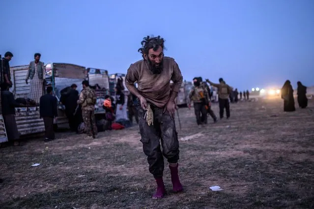 A man suspected of belonging to the Islamic State (IS) group walks past members of the Kurdish-led Syrian Democratic Forces (SDF) just after leaving IS' last holdout of Baghouz, in the eastern Syrian province of Deir Ezzor on March 4, 2019. (Photo by Bulent Kilic/AFP Photo)