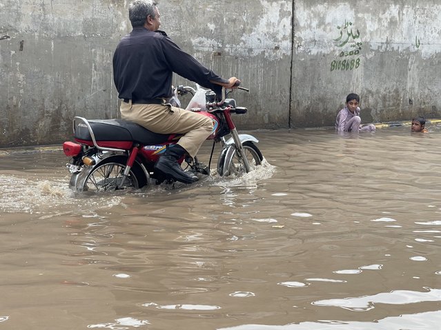 A Pakistani policeman wades across floodwaters in Lahore on August 19, 2024. Flash floods triggered by the latest spell of monsoon rains are wreaking havoc across parts of Pakistan, claiming the lives of 14 people in the previous 24 hours, an official at the provincial disaster management authority said on August 19. (Photo by Tahir Jamil Khan/Radio Free Europe/Radio Liberty)