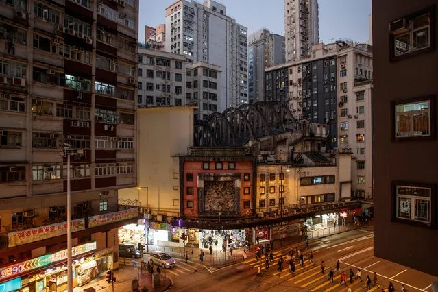 People cross the road outside the State Theatre Building that is slated for demolition in the North Point neighbourhood in Hong Kong, China, December 11, 2019. (Photo by Thomas Peter/Reuters)