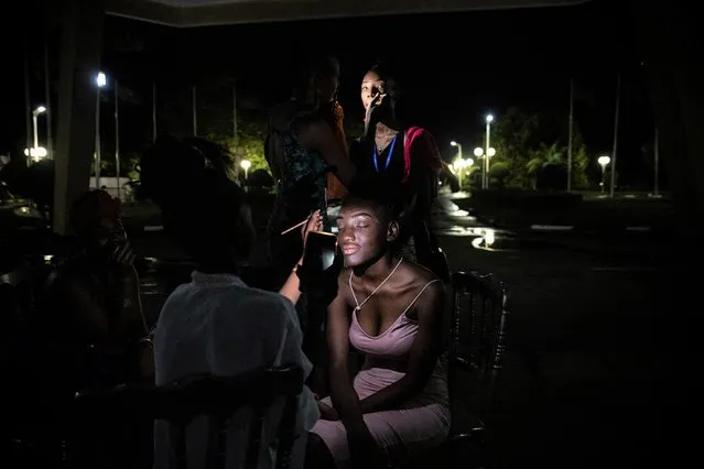 Models use their phone lights during a power outage to put on make-up before the start of the third Ouaga Fashion Week in Ouagadougou, Burkina Faso, Friday May 13, 2022. Ouaga Fashion Week returned to the Burkinabe capital after a two year COVID-19 related break. (Photo by Sophie Garcia/AP Photo)