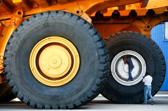 People take a selfie at the wheels of BelAZ dump trucks at the Belarusian Autoworks manufacturer in Zhodino, Belarus on August 27, 2019. (Photo by Vasily Fedosenko/Reuters)