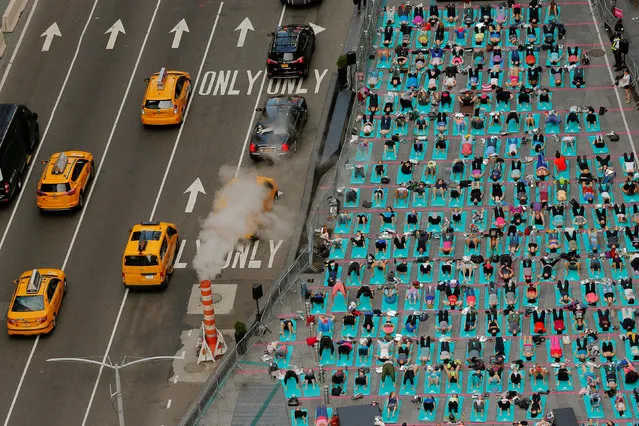People participate in a yoga class during an annual Solstice event in the Times Square district of New York, U.S., June 21, 2017. (Photo by Lucas Jackson/Reuters)