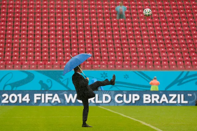 A FIFA official tests the pitch as rain pours down prior to the group G World Cup soccer match between the USA and Germany at the Arena Pernambuco in Recife, Brazil, Thursday, June 26, 2014. (Photo by Petr David Josek/AP Photo)