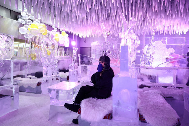 A guest sits on ice sculptor Mark Ranasinghe’s creations in freezing temperatures at Chillout Ice Lounge in Dubai, United Arab Emirates on August 28, 2023. (Photo by Amr Alfiky/Reuters)