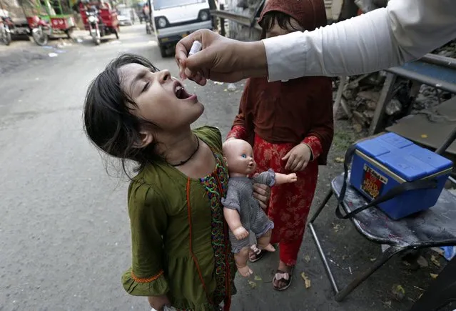 A health worker gives a polio vaccine to a girl on a street in Lahore, Pakistan, Monday, June 27, 2022. Pakistan launched a new anti-polio drive on Monday, with the goal to vaccinate a million children across Pakistan. (Photo by K.M. Chaudary/AP Photo)