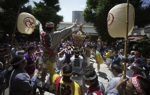 Participants clad in traditional “happi” coats swing the “mikoshi”, or portable shrine during Tenno-sai festival at Susanoo Shrine Saturday, June 3, 2017, in Tokyo. (Photo by Eugene Hoshiko/AP Photo)