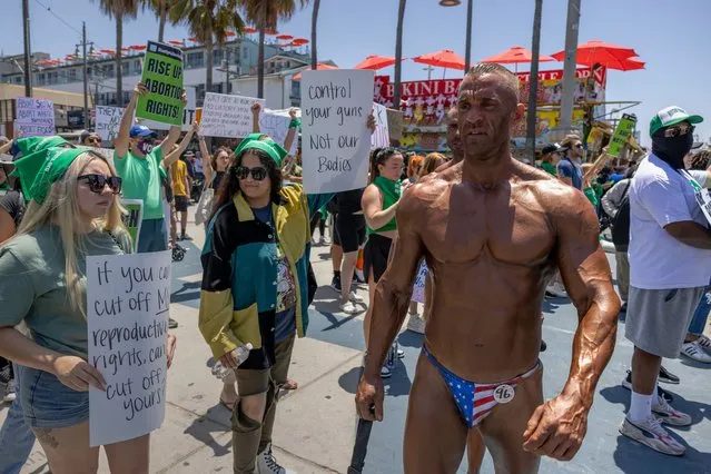 Mattias Lietgeb, from Austria, awaits the final judging results of a body building contest he is in at Muscle Beach as he passes protesters denouncing the U.S. Supreme Court on July 4, 2022 in Los Angeles, California. The Supreme Court's June 24th decision in the Dobbs v Jackson Women's Health case overturned the landmark 50-year-old Roe v Wade case, removing a federal right to an abortion. (Photo by David McNew/Getty Images)