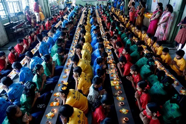Students of Shivaji Shikshan Sanstha school offer prayers after lighting the earthen lamps on the occasion of “Asadh Amavasya” in Mumbai on July 28 2022. Students lit earthen lamps and offered prayers for positivity, peace, prosperity, brotherhood and enlightenment for all. (Photo by Ashish Vaishnav/SOPA Images/Rex Features/Shutterstock)