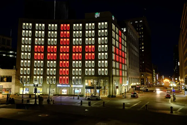 The Indianapolis Power & Light Company downtown headquarters is illuminated during a light display, Wednesday, March 25, 2020, in Indianapolis. The light display is controlled via a computer and uses energy-efficient, long-lasting bulbs to create a myriad of colors and movement. Gov. Eric Holcomb ordered state residents to remain in their homes to slow the spread of COVID-19, except when they are at work or for permitted activities. (Photo by Darron Cummings/AP Photo)