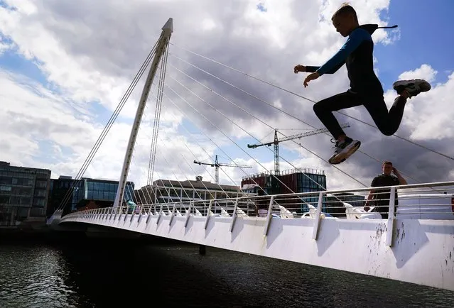 A boy jumps from the Samuel Beckett Bridge into the River Liffey on a summer day in Dublin's city centre on Friday, July 22, 2022. (Photo by Brian Lawless/PA Wire Press Association)