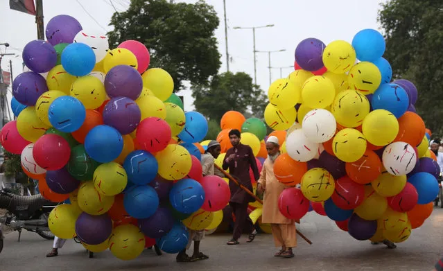 Pakistani men sell balloons after Eid al-Fitr prayers at a Mosque, in Karachi, Pakistan, 06 July 2016. Muslims around the world celebrate the Eid al-Fitr festival, which marks the end of the Muslim fasting month of Ramadan, starting 06 or 07 July, and is celebrated with prayers, readings from the Koran, and gatherings with family and friends. (Photo by Rehan Khan/EPA)