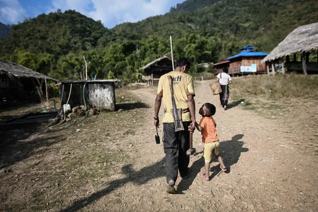 This photo taken on February 5, 2020 shows a man walking with his child ahead of the upcoming overnight ceremony by Naga tribeswomen to bless the harvest in Satpalaw Shaung village, Lahe township in Myanmar's Sagaing region. (Photo by Ye Aung Thu/AFP Photo)