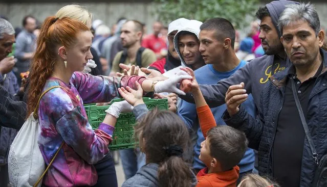 A helper distributes fruit to migrants in front of the State Office for Health and Social Affairs (LaGeSo), in Berlin, Germany, September 3, 2015. (Photo by Hannibal Hanschke/Reuters)