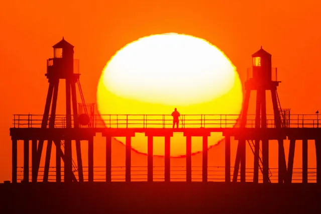 A man stands alone on the pier watching the sunrise on the North Yorkshire coast, England on March 23, 2020. (Photo by Andrew McCaren/LNP)